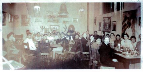 A historic photo of numerous individuals gathered around tables in a restaurant, captured in black and white.