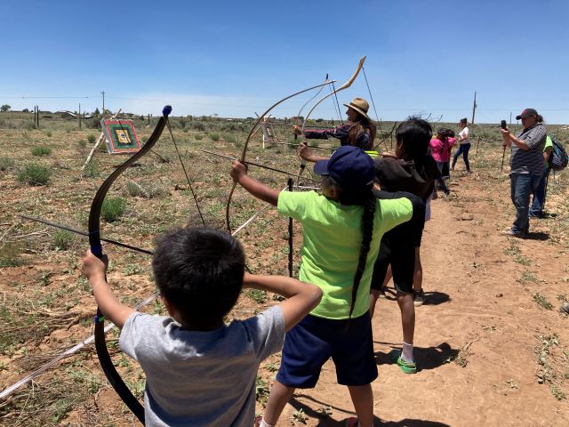 children practicing archery holding bows and arrows