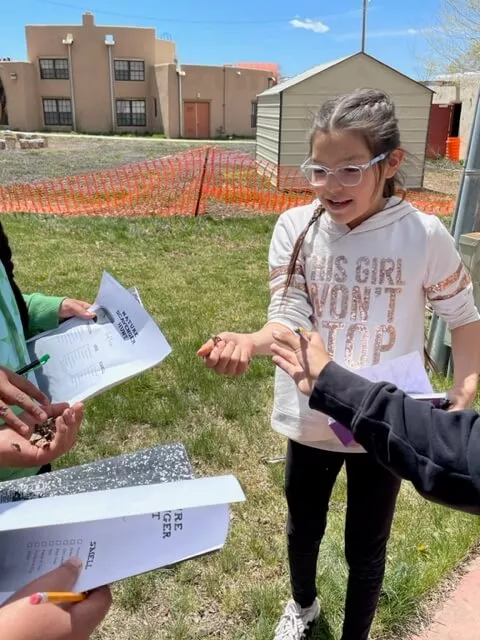 A Girl at Taos Day School Holding Up a Seed.