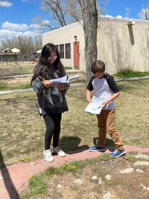 A Boy and a Girl Student at Taos Day School Reading Brochures on the Nature Scavenger Hunt.