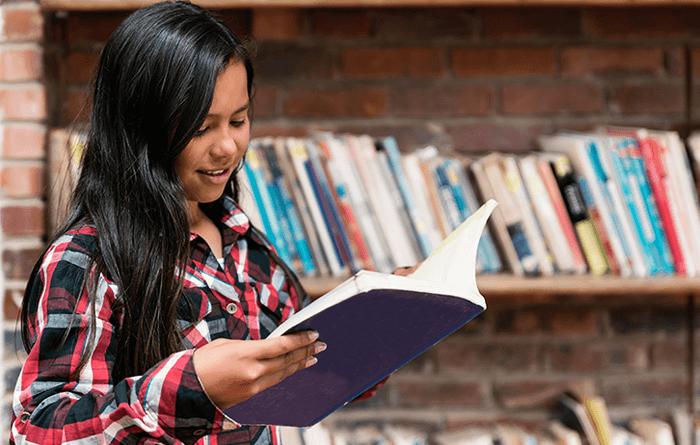 Female youth reading a book in the library.