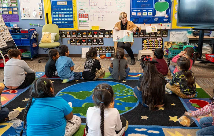 Teacher reading to a class full of students.