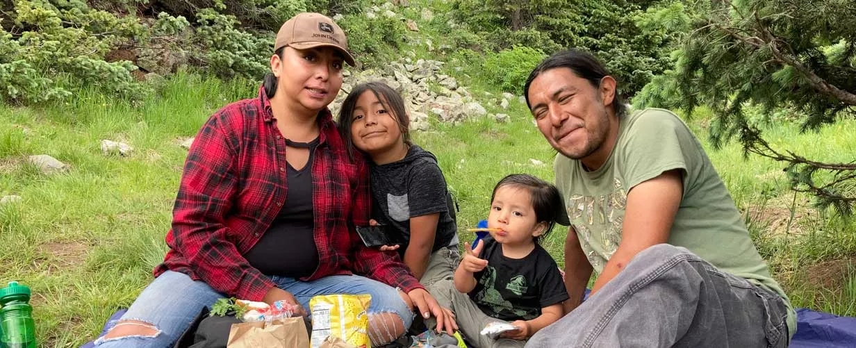Family of Four Enjoying a Picnic on the Ground Outside.
