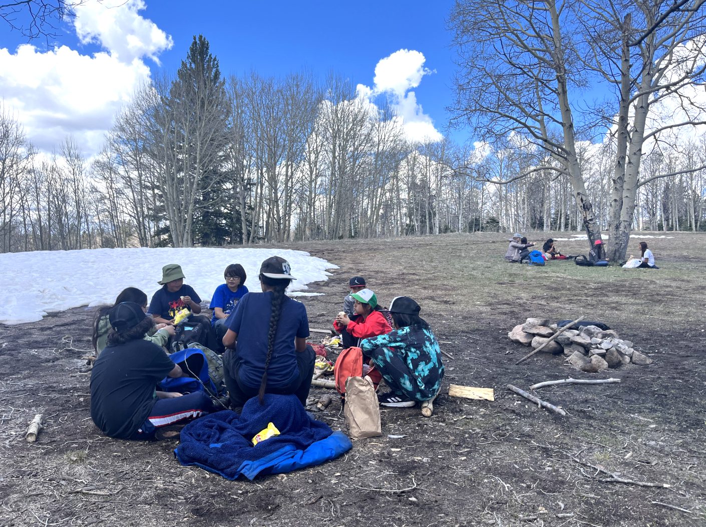 students sitting in a circle on the ground on a beautiful sunny day