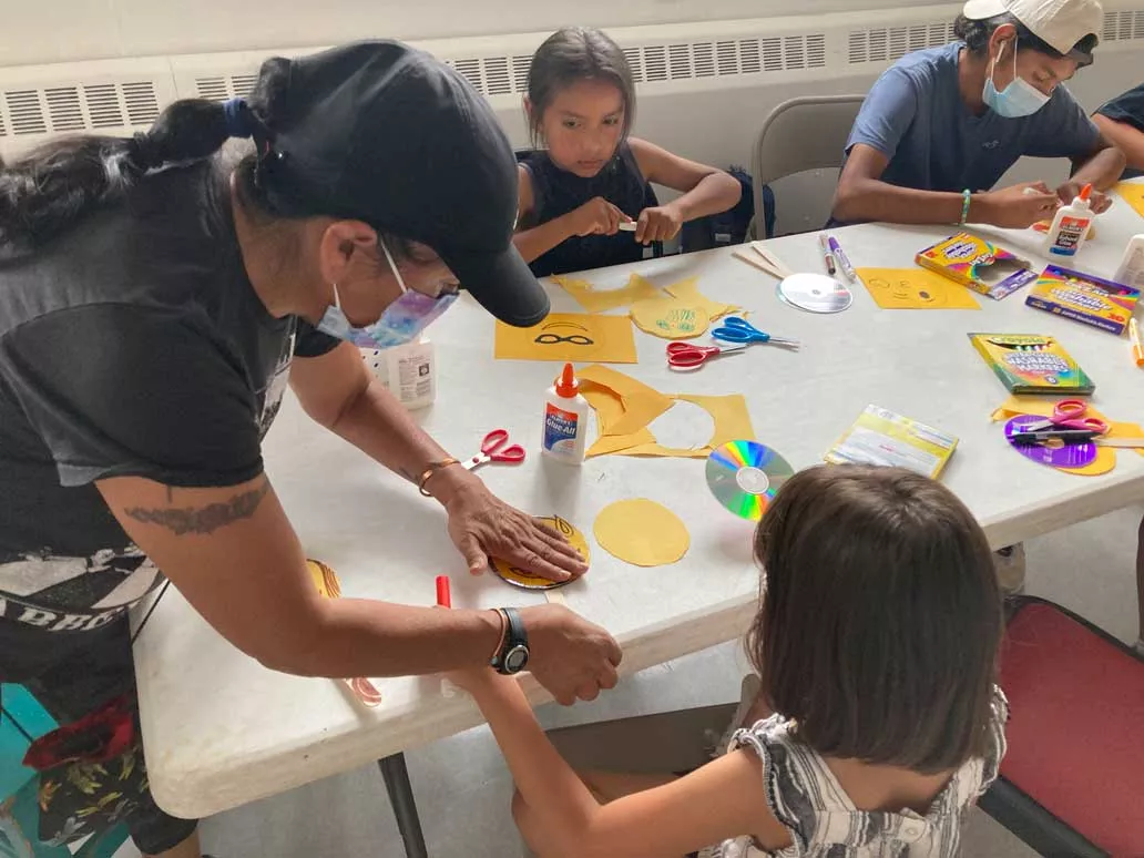 Taos Day School Teacher Helping Students at a Table with an Arts and Crafts Project.