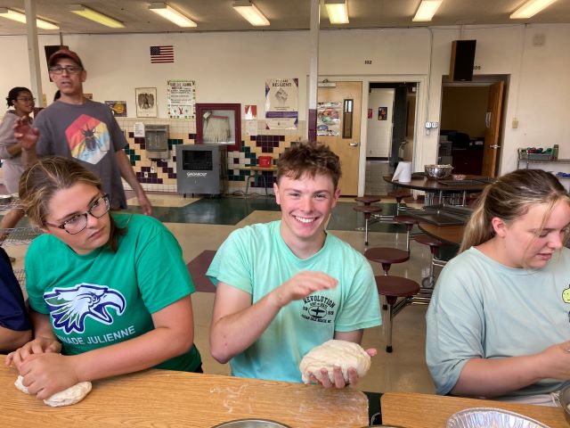 Boys and girls sitting at tables preparing dough.