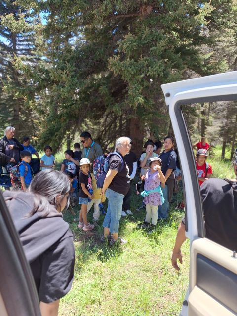 Large group of adults and children preparing to go for a hike outside.