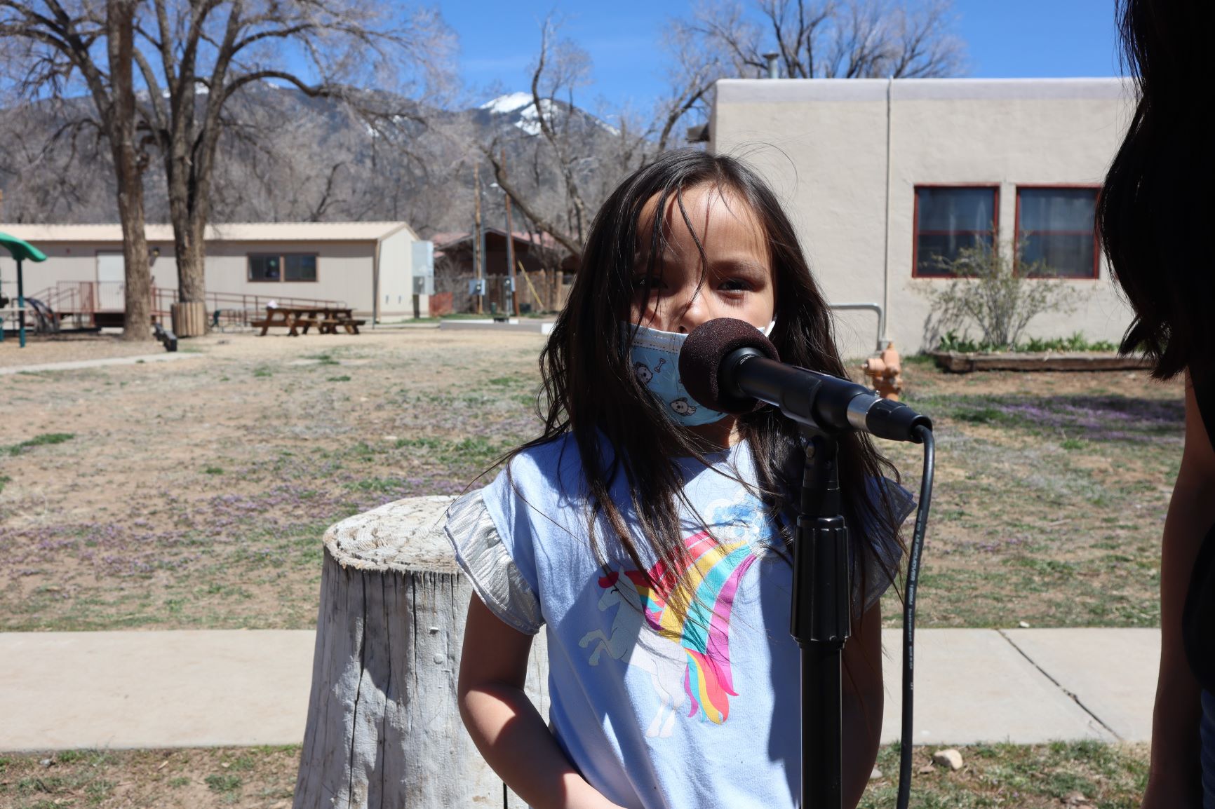 Student at Taos Day School Outside Standing In Front of a Microphone Participating in the "I Am From Poem" Project.