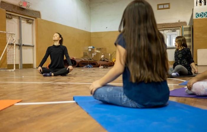 teacher leading students in yoga in the gym