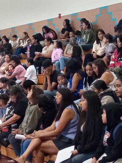 Students, parents/guardians, communit members sitting in bleachers at first day of school.